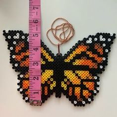 the butterfly is made out of plastic beads and has a measuring tape attached to it