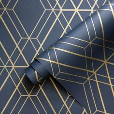 a blue and gold wallpaper with geometric design on it's side, next to a roll of tape