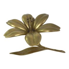 a gold metal flower with two leaves on it's back and the petals are shaped like flowers