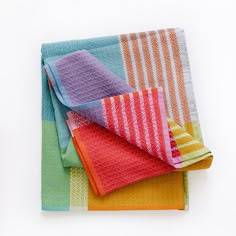 three towels folded on top of each other in different colors and patterns, with one folded up to the side