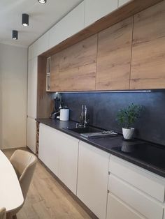 a kitchen with white cabinets and black counter tops next to a dining room table in front of a window