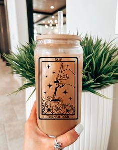 a person holding up a drink in front of a potted plant with the tart witch on it