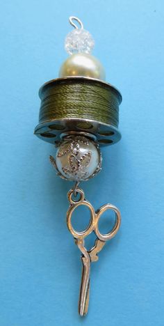 a pair of scissors and a ball of thread on a blue surface with a pearl in the center