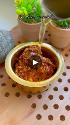 a bowl filled with food sitting on top of a wooden table next to potted plants