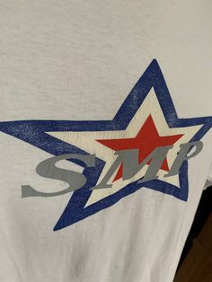 a white t - shirt with red, white and blue stars on the front that says smp