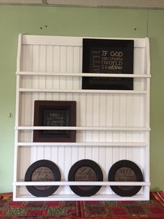 a white shelf with three black plates on it and a framed plaque above the shelves