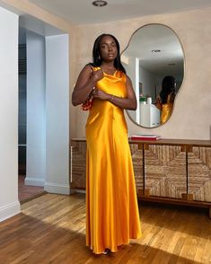 a woman standing in front of a mirror wearing an orange dress