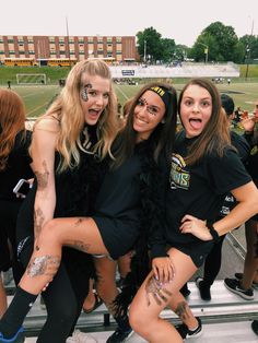 three girls posing for the camera at a football game