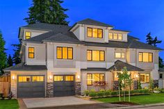 a two story house with lots of windows and lights on it's front porch