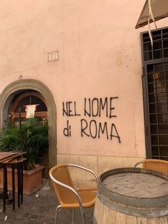 the outside of a restaurant with graffiti on the wall and wooden chairs around an outdoor table