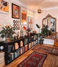 a living room filled with lots of books and plants on top of a wooden floor