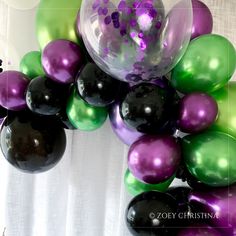 a bunch of balloons that are in the shape of a grapevine with purple, green and black ones