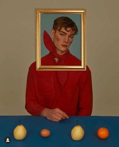 a painting of a man in red shirt with pears and oranges on blue table