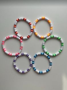 four bracelets with different colors are arranged in a circle on a white table top