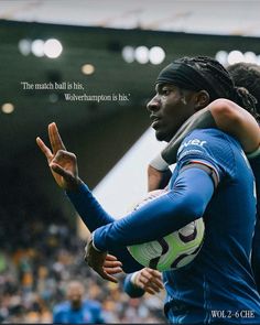 two soccer players hugging each other in front of a crowd with a quote on it