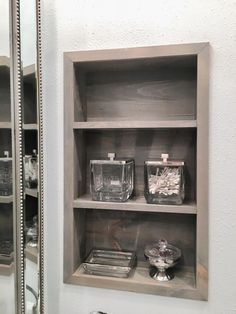 an empty shelf in the corner of a bathroom next to a mirror and other items