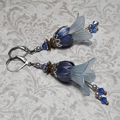 BLUE FAIRYCORE EARRINGS ▪️▪️▪️▪️▪️▪️▪️️▪️▪️▪️▪️▪️▪️ These vintage flower fairy inspired lily flower earrings are made with Lucite flowers that have been given a beautiful hand painted gold shimmer. Beautiful sparkling sapphire blue crystals and tiny lavender blue pearls hang from delicate drops and catch the light as they move.  Both antique bronze and silver tone ornate floral bead caps have been used to give an art nouveau feel and they are finished with lead, nickel and cadmium free lever bac Blue Earrings Aesthetic, Cute Jewellery, Lucite Earrings, Blue Flower Earrings, Lucite Flowers, Fantasy Earrings, Vintage Inspired Earrings, Beautiful Crystals, Estilo Hippie