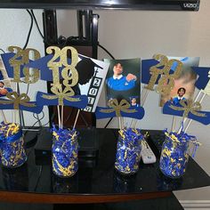 blue and gold centerpieces are displayed on a table in front of a television