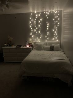 a bed with white sheets and lights on the wall