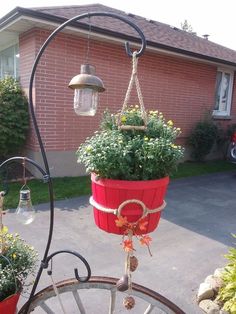 a red pot with flowers hanging from it's side in front of a house