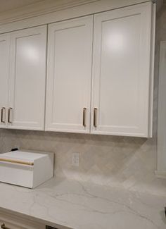 a kitchen with white cupboards and marble counter tops in the middle of the room