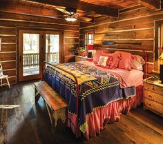 a bed in a room with wooden walls and flooring next to a table lamp