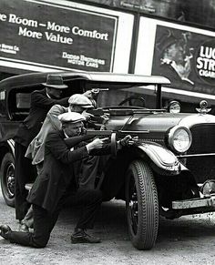 an old black and white photo of a man standing next to a truck