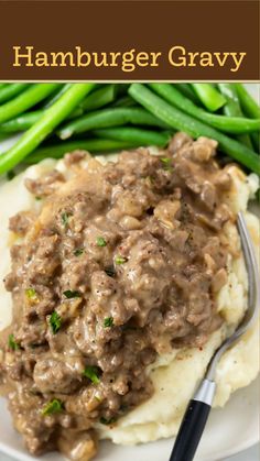 a white plate topped with mashed potatoes covered in gravy and green beans