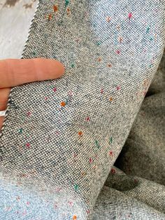 a person's finger is on the back of a gray and multicolored fabric