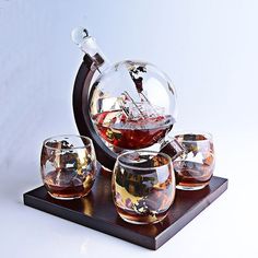 four wine glasses and a decanter on a wooden stand