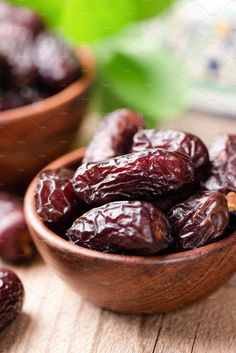 some raisins are in a wooden bowl on a table next to other raisins