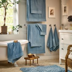 a bathroom with blue towels hanging on the wall and a bathtub in the corner