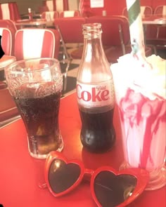 two coke bottles and sunglasses on a table