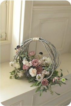 a white and pink flower arrangement sitting on top of a counter next to a window