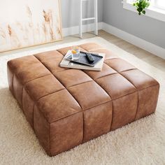 a brown leather ottoman sitting on top of a white rug