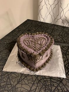 a heart shaped cake sitting on top of a piece of tin foil covered in frosting