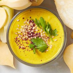 a bowl filled with yellow soup surrounded by sliced apples