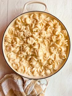 a pot filled with macaroni and cheese on top of a wooden table