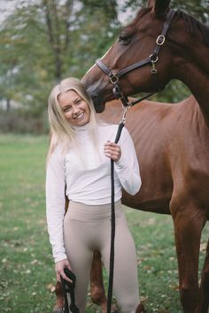 a woman standing next to a brown horse