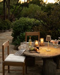 an outdoor table with candles and flowers on it in the middle of a garden area