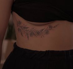 a close up of a woman's stomach with flowers and leaves tattooed on it