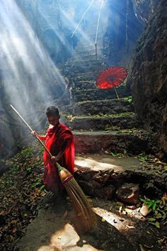 a man sweeping up some stairs with a broom and an orange umbrella in the air