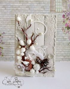 a card with white flowers and pineconis on it, in front of a brick wall