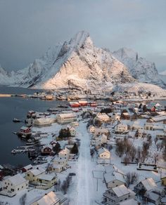 an aerial view of a town with mountains in the background and snow on the ground