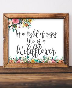 a wooden frame with the words in a field of roses she is a wildflower