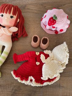 three crocheted dolls are laying on a wooden floor next to hats and shoes