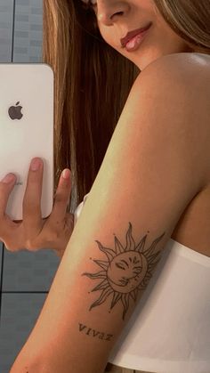 a woman with a sun tattoo on her arm holding an ipad in front of her