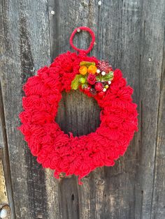 a red knitted wreath hanging on a wooden fence