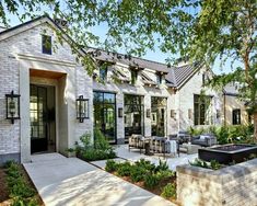 a white brick house with an outdoor seating area and fire pit in the front yard