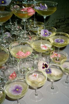 there are many wine glasses that have flowers in them on the glass rimmed dishes